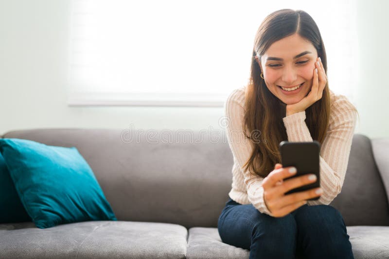 Woman smiling while reading a sweet text message on her phone – the joy of receiving loving words.